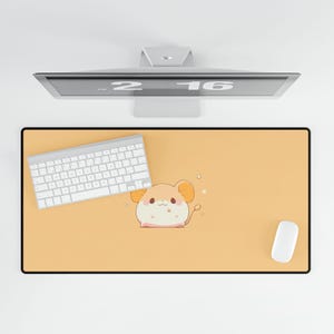 May include: A rectangular mouse pad with a black border and a light orange surface. A cartoon mouse illustration is centered on the pad. A white keyboard and mouse are on the pad. A computer monitor is above the pad.