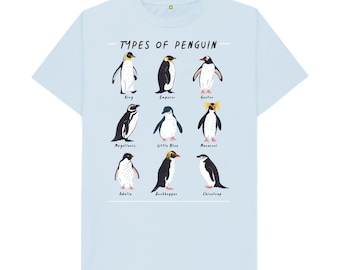 Puede incluir: Una camiseta azul claro con un gráfico de diferentes tipos de pingüinos. El texto "Types of Penguin" está impreso en la parte superior del gráfico. Los nombres de cada pingüino están impresos debajo del gráfico.