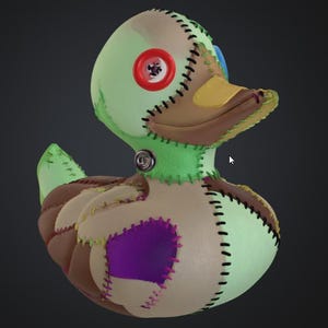May include: A handmade patchwork duck toy. The duck has a green head, brown and beige body, and a yellow beak. It features a red button eye and is stitched together with various coloured threads. A unique and whimsical creation.