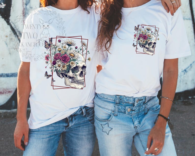 Peut inclure: Deux t-shirts blancs avec un motif de cr&acirc;ne. Le cr&acirc;ne est entour&eacute; de fleurs et de papillons. Le texte "TWENTY TWO KANGAROOS" est sur le t-shirt de gauche.