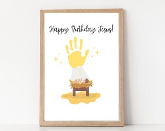 May include: A framed print with the text "Happy Birthday Jesus!" features a yellow handprint above a depiction of the nativity scene. The image includes a baby in a manger, with a yellow glow and star accents.