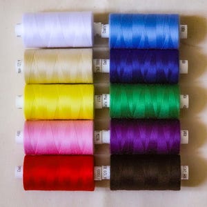May include: A set of ten spools of thread in various colours, including white, beige, yellow, pink, red, purple, green, blue, and brown. The spools are labelled with the brand name "Coats" and the length of the thread in yards.