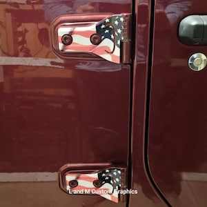 May include: Close-up of a maroon vehicle door with decorative hinges featuring a red, white, and blue American flag design. The door handle is black, and the lock is silver. The text "L and M Custom Graphics" is visible.