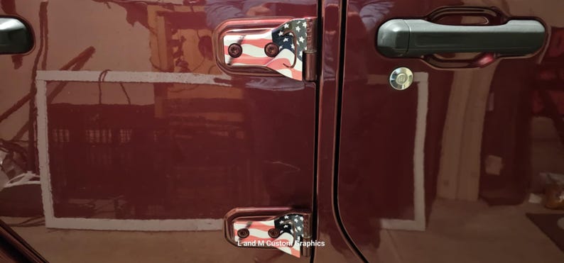 May include: Close-up of a maroon vehicle door with decorative hinges featuring a red, white, and blue American flag design. The door handle is black, and the lock is silver. The text "L and M Custom Graphics" is visible.