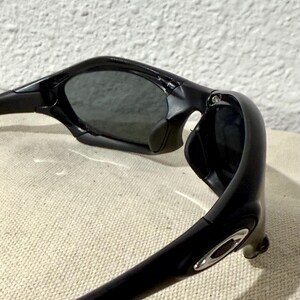 K&ouml;nnte beinhalten: Schwarze Sonnenbrille mit einem schlanken, modernen Design. Die Sonnenbrille hat dunkle Gl&auml;ser und einen gl&auml;nzend schwarzen Rahmen. Der Rahmen hat einen silbernen Akzent in der N&auml;he des B&uuml;gels. Die Sonnenbrille ist abgewinkelt und zeigt Form und Stil.