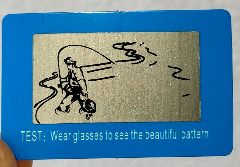 May include: A blue rectangular card with a silver rectangle in the center. The silver rectangle has a black illustration of a person fishing. The text at the bottom says, "TEST: Wear glasses to see the beautiful pattern."