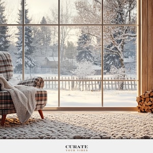 May include: An armchair upholstered in a plaid fabric with a beige and brown knit throw blanket draped over it, positioned on a thick textured rug in front of a large window overlooking a snowy landscape with trees and a wooden fence.