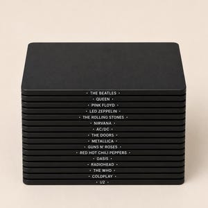 Puede incluir: Una pila de dieciséis posavasos cuadrados negros con esquinas redondeadas. Cada borde del posavasos presenta el nombre de una banda impreso en blanco, incluyendo The Beatles, Queen, Pink Floyd, Led Zeppelin, The Rolling Stones, Nirvana, AC/DC, The Doors, Metallica, Guns N' Roses, Red Hot Chili Peppers, Oasis, Radiohead, The Who, Coldplay y U2.
