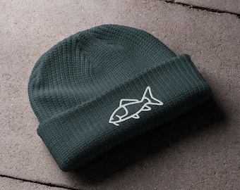 Puede incluir: Un gorro de lana verde oscuro con un diseño de pez bordado en blanco.