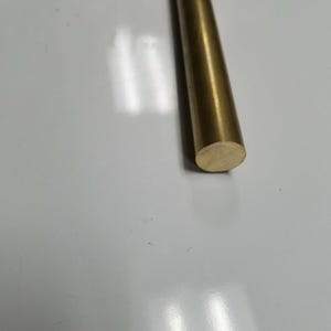 May include: A close-up of a gold-colored metal rod with a rounded end.