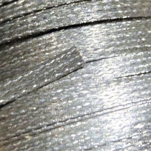 May include: Close-up of silver metallic cord, showing the individual strands of wire that make up the cord.