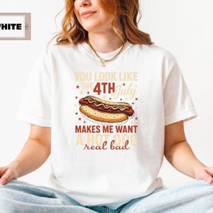 May include: White t-shirt with a red, white, and blue graphic of a hot dog and the text "You look like the 4th of July makes me want a hot dog real bad."