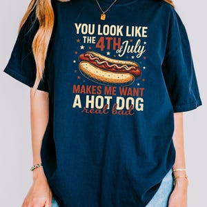May include: A navy blue t-shirt with a graphic of a hot dog and the text "You look like the 4th of July makes me want a hot dog real bad".