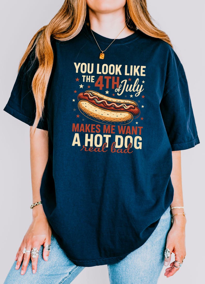 May include: A navy blue t-shirt with a graphic of a hot dog and the text "You look like the 4th of July makes me want a hot dog real bad".