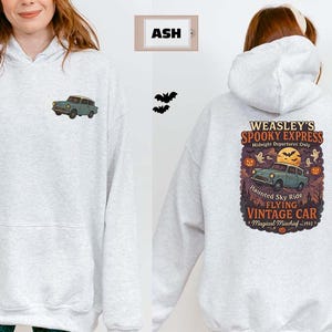 May include: Light gray hoodie with a front pocket and a small car graphic on the front. The back features a vintage car design with text that reads "WEASLEY'S SPOOKY EXPRESS" and "FLYING VINTAGE CAR". Halloween-themed design.