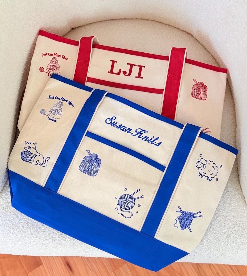 May include: Two canvas tote bags with red and blue trim. The top bag features red embroidery with the letters LJI and a gnome graphic. The bottom bag features blue embroidery with the text Susan Knits, a cat, a sheep, and yarn motifs.