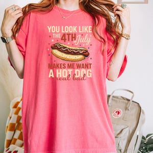 May include: Pink t-shirt with a graphic of a hot dog and the text "You look like the 4th of July makes me want a hot dog real bad".