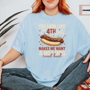 May include: Light blue t-shirt with a graphic of a hot dog and the text "You look like the 4th of July makes me want a hot dog real bad".