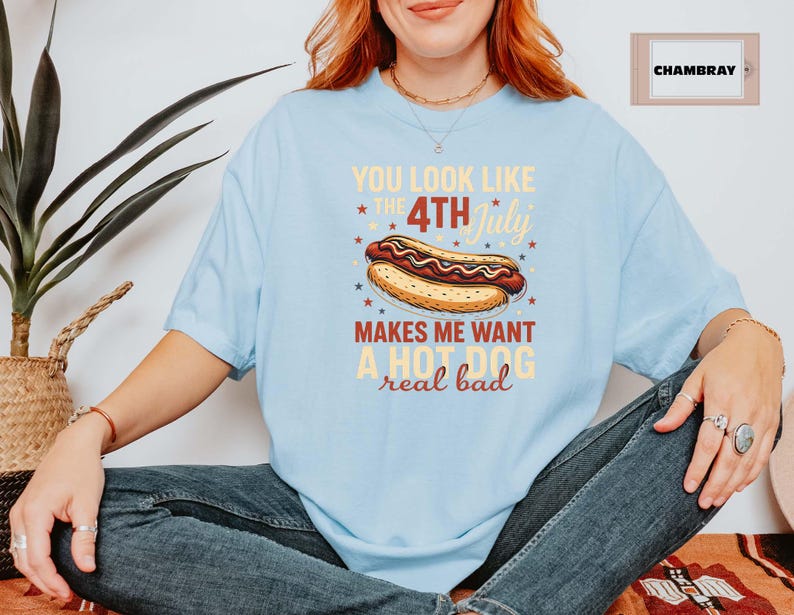May include: Light blue t-shirt with a graphic of a hot dog and the text "You look like the 4th of July makes me want a hot dog real bad".