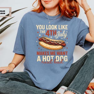 May include: A blue t-shirt with the text "You look like the 4th of July makes me want a hot dog real bad" printed on it.