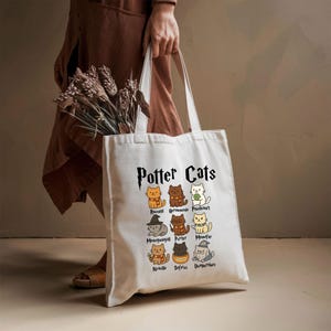 May include: White canvas tote bag with the text "Potter Cats" in black. The bag features a graphic of nine cats with names like "Ronald", "Hermione", and "Pawsdemort" underneath each cat.