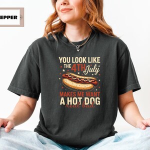 May include: A dark gray t-shirt with a graphic print of a hot dog and the text "You look like the 4th of July makes me want a hot dog real bad".