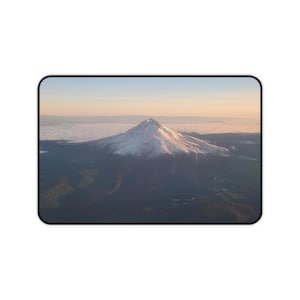 Puede incluir: Una vista aérea de un pico de montaña cubierto de nieve con un cielo nublado en el fondo.