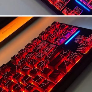 May include: A black mechanical keyboard with red and blue LED lights. The keycaps have a spiderweb design and are illuminated with red light. The keyboard has a variety of keys, including function keys, arrow keys, and number keys.