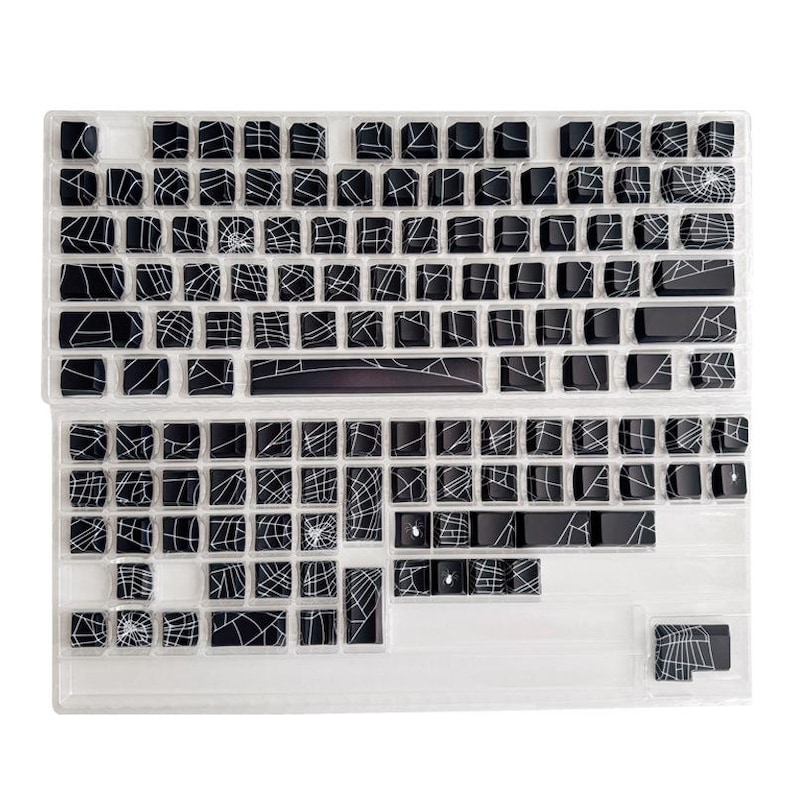 May include: Black and white keyboard keycaps with a spiderweb design. The keycaps are arranged in a standard keyboard layout.