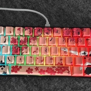 May include: A 60% mechanical keyboard with custom keycaps featuring a colorful rainbow gradient and a black and white anime-style illustration of a woman with cherry blossoms. The keycaps are made of ABS plastic and have a textured finish.