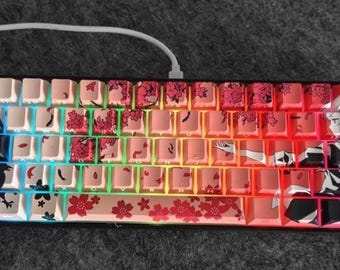 May include: A 60% mechanical keyboard with custom keycaps featuring a colorful rainbow gradient and a black and white anime-style illustration of a woman with cherry blossoms. The keycaps are made of ABS plastic and have a textured finish.