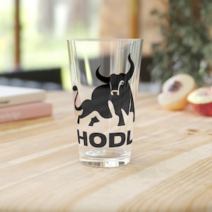 May include: A clear glass with a black bull silhouette and the word "HODL" printed on it.