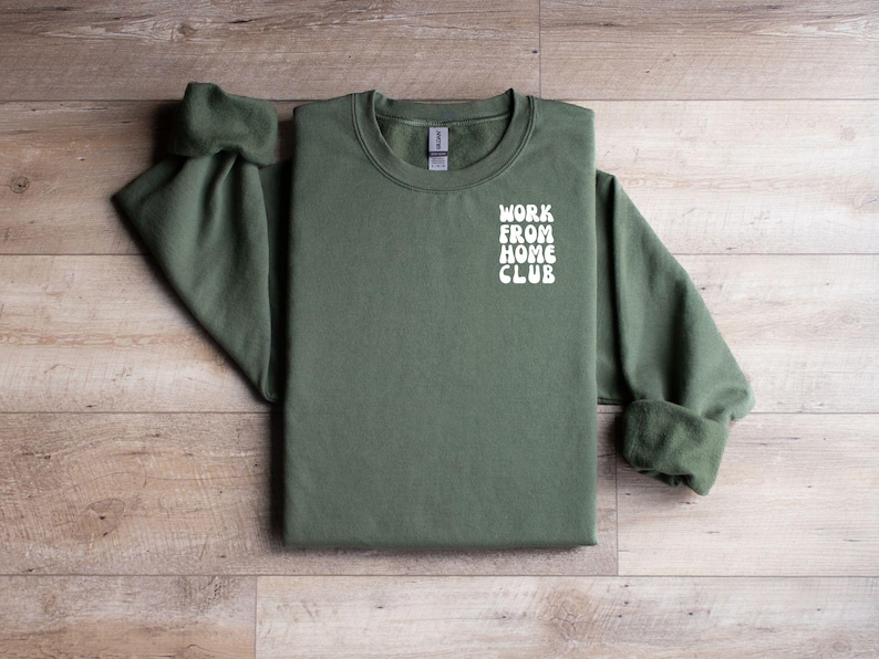 K&ouml;nnte beinhalten: Ein gr&uuml;ner Pullover mit dem Text "WORK FROM HOME CLUB" in Wei&szlig; auf der Vorderseite.
