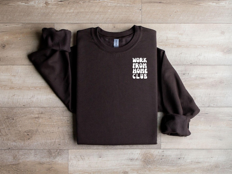 K&ouml;nnte beinhalten: Ein braunes Sweatshirt mit dem Text "WORK FROM HOME CLUB" in Wei&szlig; auf der Vorderseite.
