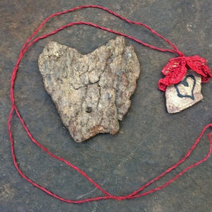 May include: A red string necklace with a heart-shaped pendant made of wood and a crocheted red heart charm.
