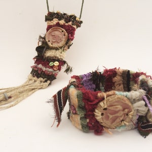 May include: A set of two handmade bracelets with a woven fabric design. The bracelets are decorated with colorful fabric scraps, beads, and clay embellishments. The bracelets are a unique and stylish accessory.