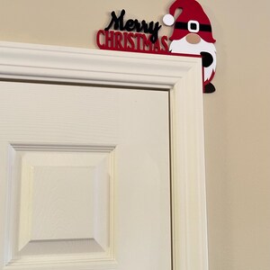 Farther shot showing the small gnome door corner topper on a white paneled door against a neutral wall.