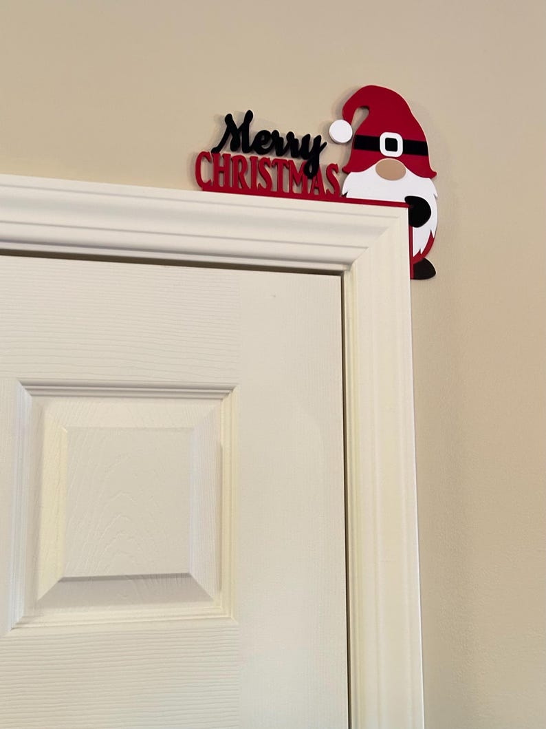 Farther shot showing the small gnome door corner topper on a white paneled door against a neutral wall.