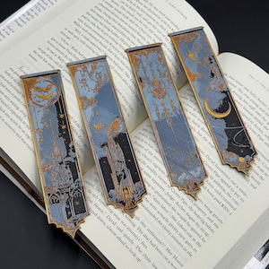 Peut inclure: Ensemble de quatre marque-pages en métal décoratifs dans un schéma de couleurs bleu et or. Chaque marque-page représente une scène différente avec un château, des étoiles et une lune croissante. Les marque-pages sont conçus pour être utilisés avec des livres.