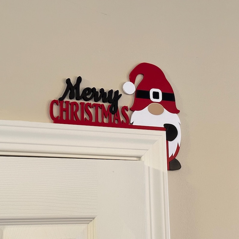 Detailed close-up of the red and black Merry Christmas gnome door corner sign positioned on a white door frame.