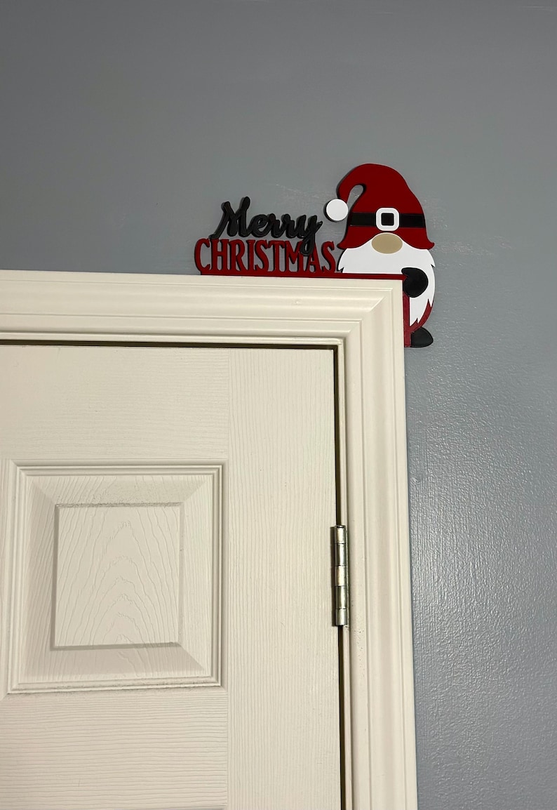 A slightly angled shot of the top right corner of a white door featuring the festive gnome decoration on a grey wall.