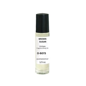 May include: A clear glass roll-on bottle with a black cap. The label reads "BROWN SUGAR Unisex Fragrance Body Oil O-B073 QUEEN2KEEPUP 1/3 oz."