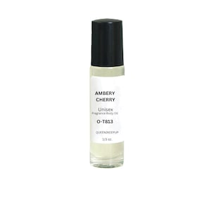 May include: A clear glass bottle with a black roll-on top. The bottle contains a fragrance body oil labeled "Ambery Cherry" with the text "Unisex Fragrance Body Oil" and "O-T813 QUEEN2KEEPUP 1/3 oz."