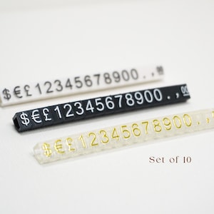Peut inclure: Trois étiquettes de prix en plastique blanc, noir et transparent. Chaque bande affiche des chiffres et des symboles monétaires. Le texte "Set of 10" et "DIY in a Sec" sont également visibles.