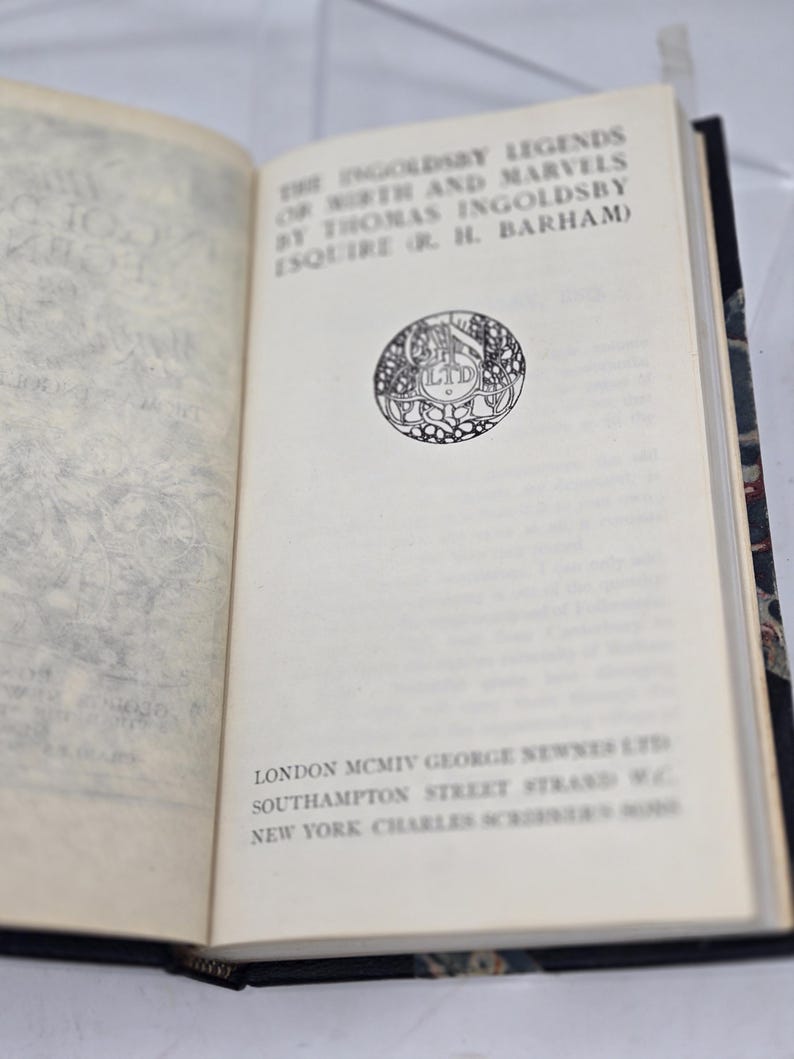 May include: A book titled "The Ingoldsby Legends of Mirth and Marvels by Thomas Ingoldsby Esquire (or R. H. Barham)" with a black and white illustration of a circular logo on the cover. The book was published in 1904 by George Newnes Ltd in London and Charles Scribner's Sons in New York.
