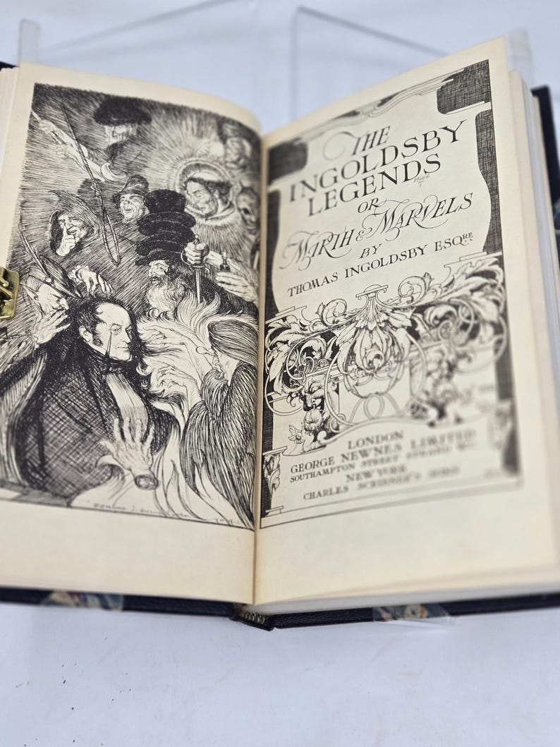 May include: An open book with a black and white illustration on the left page and the title "The Ingoldsby Legends or Mirth & Marvels by Thomas Ingoldsby Esq" on the right page.