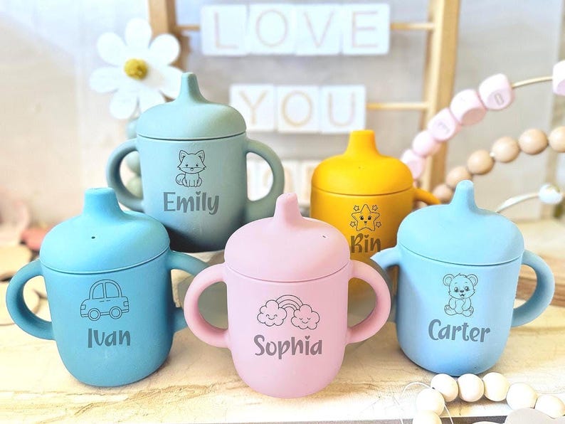 Pode incluir: Quatro copos de silicone coloridos com al&ccedil;as e tampas. Cada copo tem um design e um nome diferente: Emily, Ivan, Sophia e Carter.