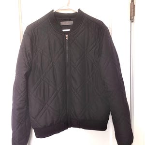 May include: Black quilted bomber jacket with a zip closure. The jacket has a diamond pattern and a ribbed hem.