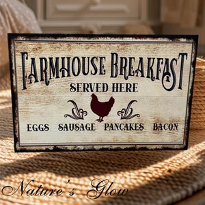 May include: Rustic farmhouse style sign with the text "Farmhouse Breakfast Served Here" and a silhouette of a chicken. Below the text are the words "Eggs, Sausage, Pancakes, Bacon".