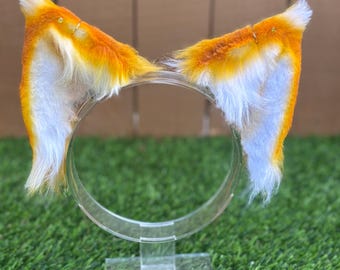 May include: A pair of orange and white cat ears headband. The headband is made of a soft, fluffy material and is perfect for adding a touch of whimsy to any outfit.